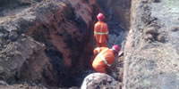 Men working in deep trenches with required PPE.